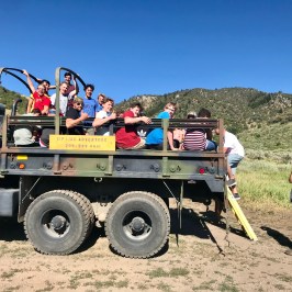 Group of zipliners packed into the back of the green army truck