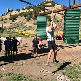 boy hanging off the ground in the adventure park