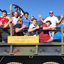 group waving at the camera in the back of the green army truck