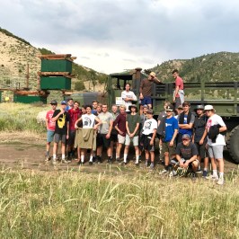 group of boys posing in front of the big green army truck
