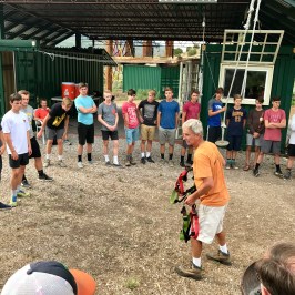 staff teaching large group of boys how to harness up for the zipline
